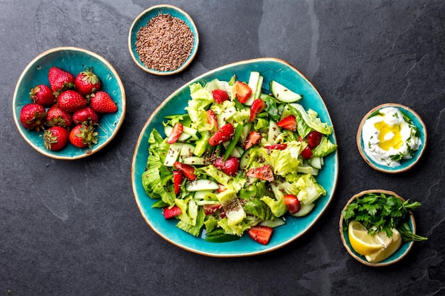 Salade de laitue saine aux fraises avec des graines de lin sur la vue de dessus de plaque d'immatriculation bleue