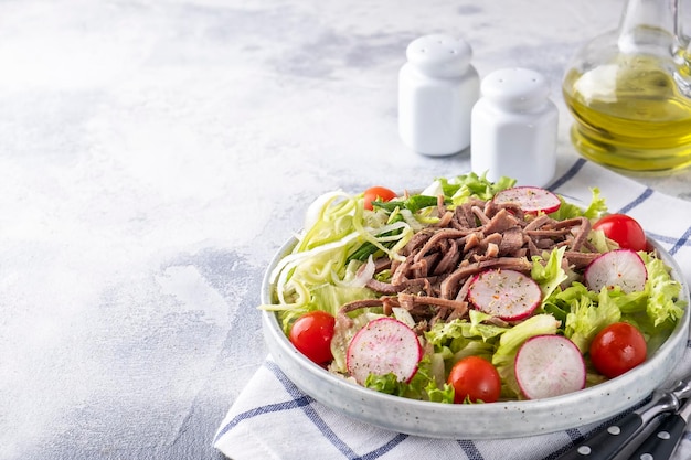 Salade avec langue de boeuf et légumes frais sur une assiette. Espace texte