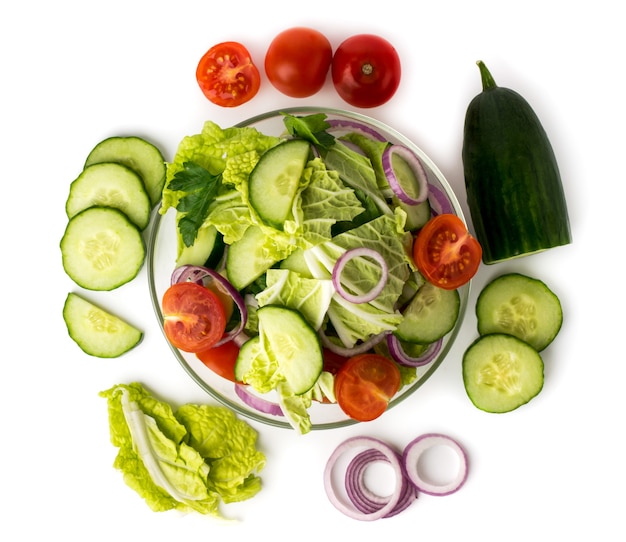 Salade de légumes en assiette et ingrédients avec lesquels elle est faite sur un fond blanc. La vue du haut.