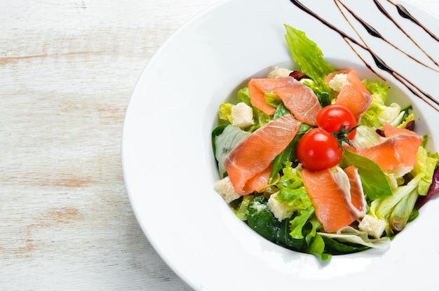 Photo salade de légumes au saumon salé et tomates cerises. salade césar au saumon. vue de dessus. espace libre pour votre texte.