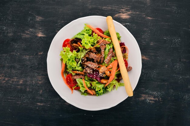 Salade de légumes au veau et aux champignons Sur un fond en bois noir Vue de dessus Copier l'espace pour votre texte