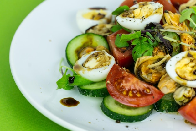 Une salade de légumes aux moules et œufs de caille sur une assiette blanche