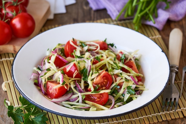 Salade de légumes aux tomates cerises, chou et oignons rouges dans un bol blanc