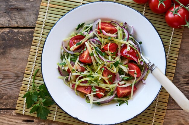 Salade de légumes aux tomates cerises, chou et oignons rouges dans un bol blanc