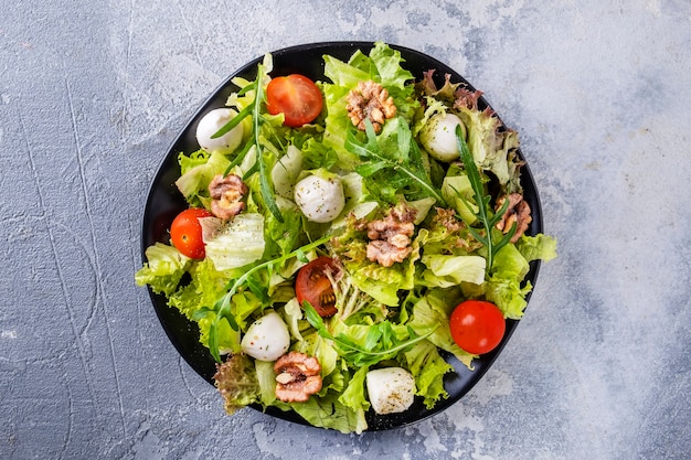 Salade de légumes aux tomates, fromage, roquette et noix. Vue de dessus