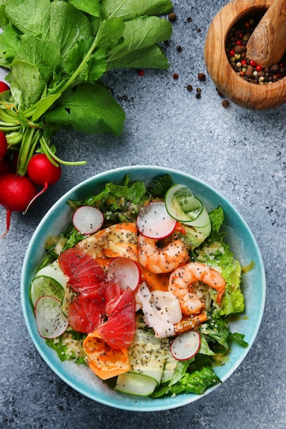 Salade de légumes et crevettes et saumon vue de dessus en gros plan avec des ingrédients sur une table en béton