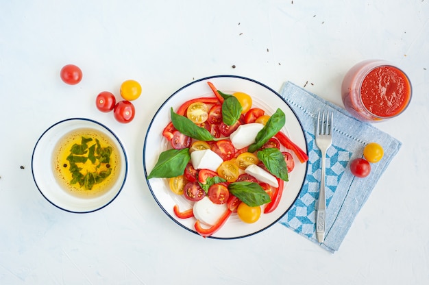 Salade de légumes d'été au fromage et basilic. Sauce et jus de tomate dans un verre.