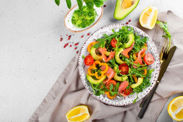 Salade De Légumes D'été Frais Avec Roquette, Tomates, Poivrons, Avocat Et Saumon Sur Une Assiette Vue De Dessus.