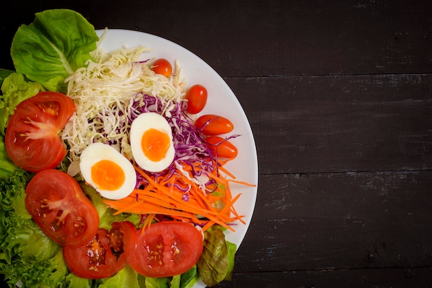 Salade de légumes sur fond de bois noir