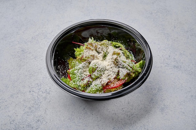 Salade de légumes frais au fromage dans un récipient en plastique noir