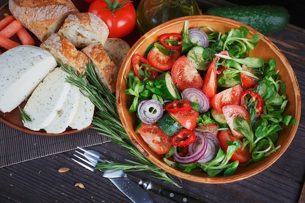 Salade de légumes frais aux tomates, concombres et oignons. Servi avec fromage, légumes, huile d'olive et pain