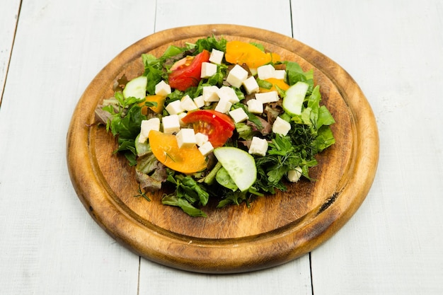 Salade de légumes frais avec concombre de tomates au fromage de verdure sur une table en bois blanche