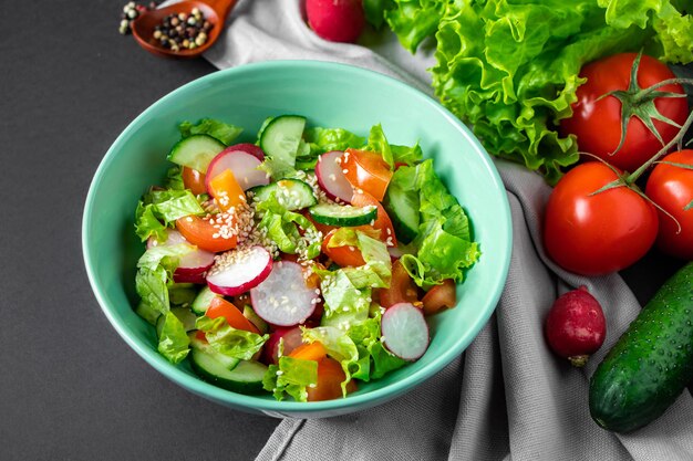 Salade de légumes frais dans un bol en céramique sur fond gris Plat d'été saisonnier