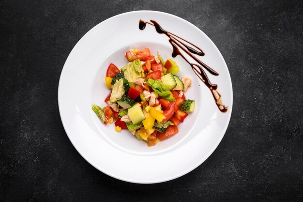 Salade de légumes frais et filet de poulet sur une assiette blanche