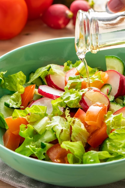 Salade de légumes frais à l'huile d'olive dans un bol en céramique sur fond de bois