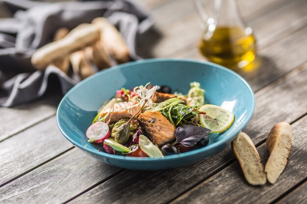 Salade de légumes frais à l'huile d'olive de saumon rôti et baguette.