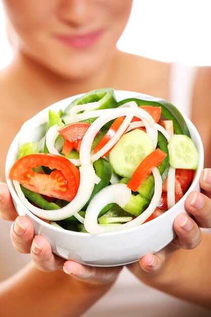 une salade de légumes frais avec une jolie femme la tenant en arrière-plan