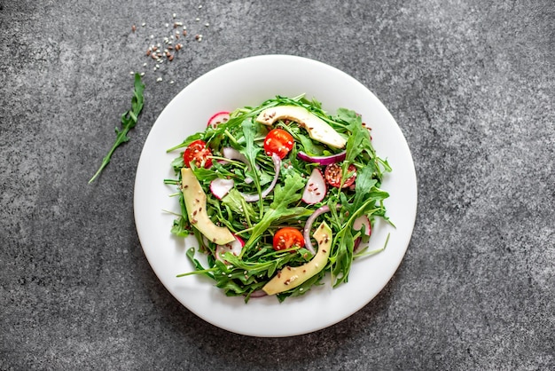 Salade de légumes frais sains tomates roquette avocat radis sur fond de pierre