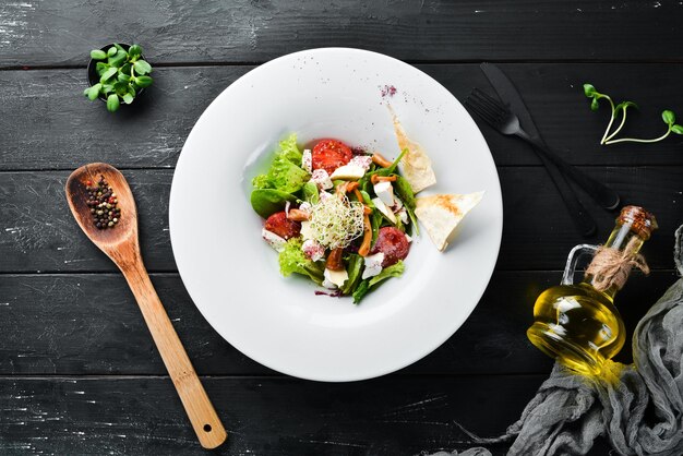 Salade de légumes avec fromage brie, tomates cerises et épinards. Dans l'assiette. Vue de dessus. Espace libre pour votre texte. Style rustique.