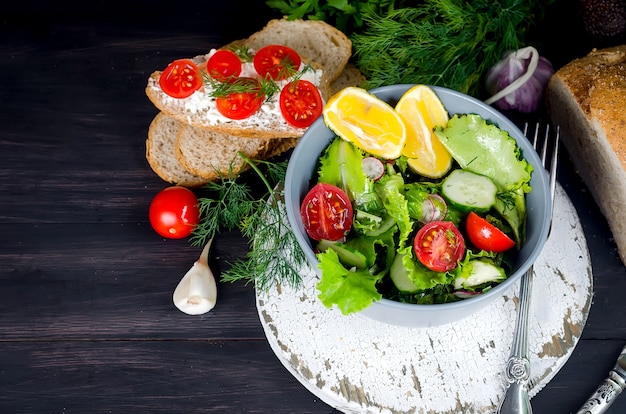 Salade de légumes de laitue fraîche, tomates, concombres, radis et oignons sur table.