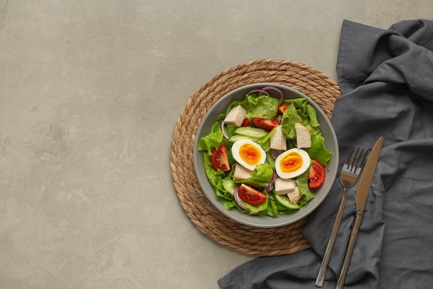 Salade de légumes avec un œuf sur fond gris