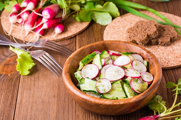 Salade de légumes de printemps dans une assiette en bois