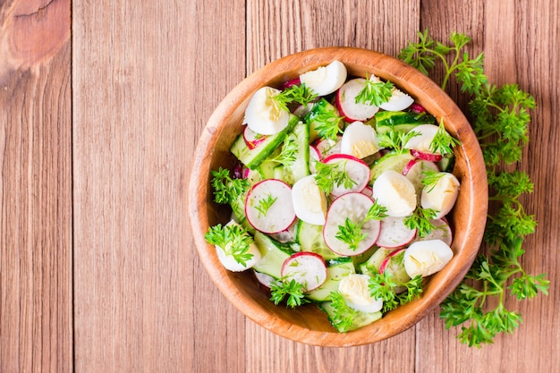 Salade de légumes de printemps dans une assiette en bois