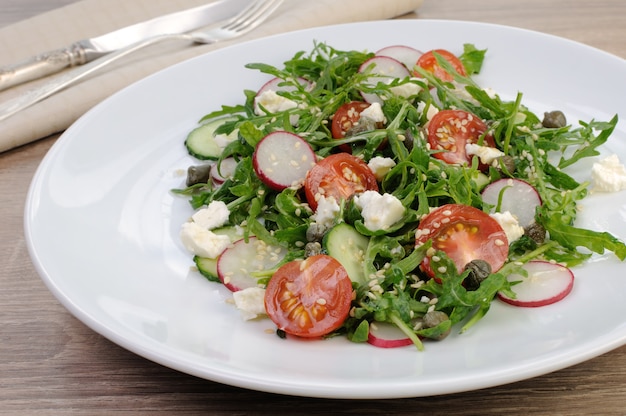 Salade de légumes avec roquette, feta, vinaigrette aux olives et graines de sésame