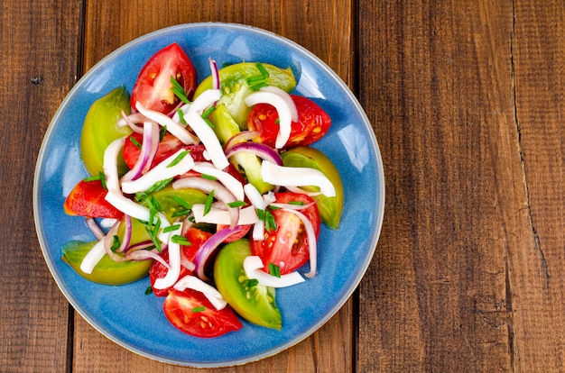 Salade de légumes sains avec tomates et morceaux de calamars. Studio photo.