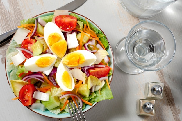 Salade de légumes sur une table en bois blanche