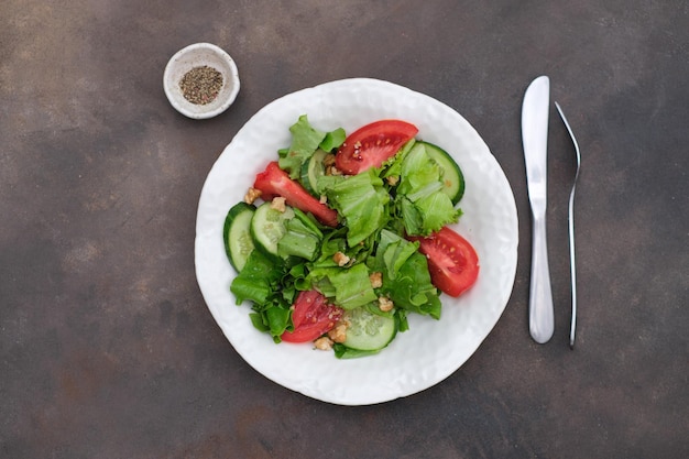 salade de légumes tomates salade de concombres sur une assiette blanche sur un fond brun foncé alimentation saine
