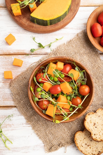 Salade de légumes végétariens de tomates citrouille pousses de pois microgreen sur fond de bois blanc vue de dessus