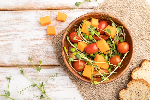 Salade de légumes végétariens de tomates citrouille pousses de pois microgreen sur fond de bois blanc vue de dessus