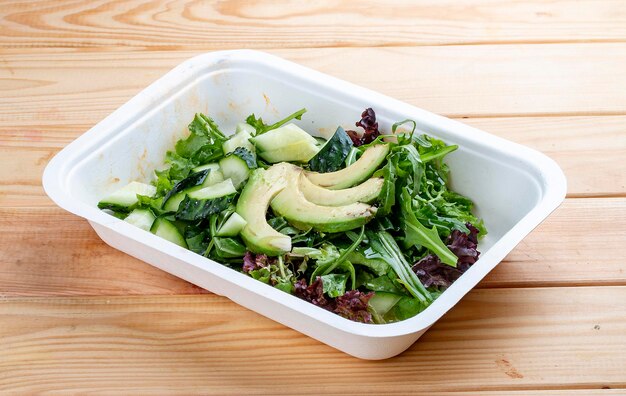 Photo salade avec des légumes verts et de l'avocat nourriture végétarienne nourriture à emporter sur un fond en bois