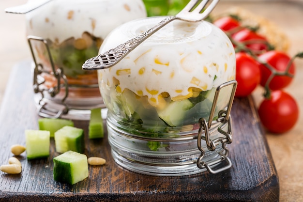 Salade maison en bocal en verre à l&#39;envers sur une planche à découper en bois.