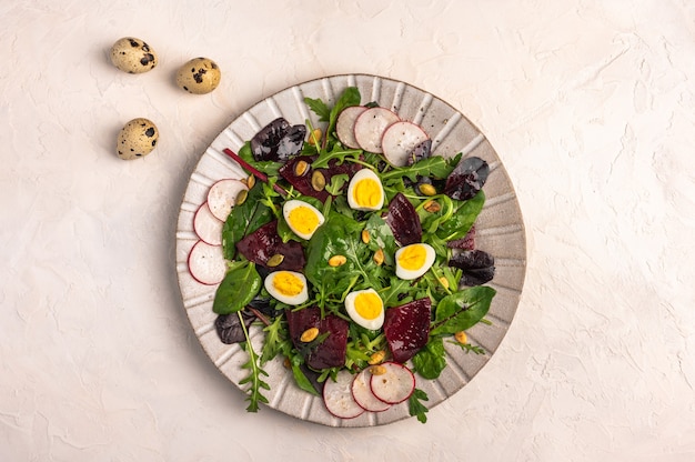 Salade maison d'œufs de caille, betterave bouillie, radis, roquette et basilic à l'huile d'olive sur une lumière