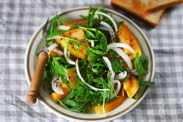 Salade maison saine avec roquette et tomate jaune sur une assiette.