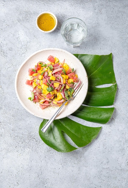 Photo salade de mangue de thon tropicale hawaïenne tahitienne sur une assiette blanche sur une feuille de monstera tropicale