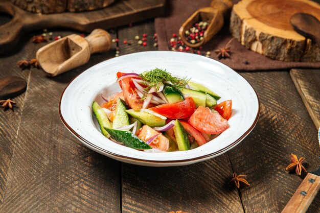 Salade de mélange de légumes frais sur une plaque blanche sur la table en bois