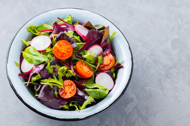 Salade avec mélange de verts sur fond gris