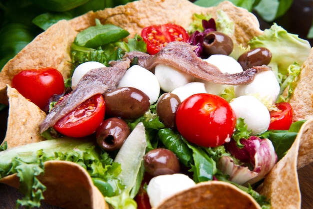 salade mixte avec mozzarella et anchois dans une corbeille à pain