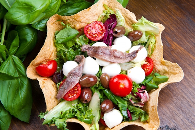 salade mixte avec mozzarella et anchois dans une corbeille à pain