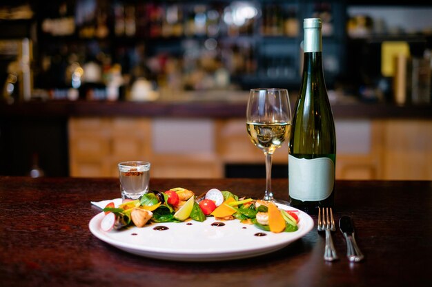 Salade de moules sur une assiette blanche avec verre et bouteille de vin sur le fond du bar Concept d'un beau plat servant pour un restaurant