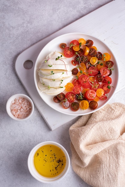 Salade de mozzarella et tomates cerises à l'huile d'olive sur fond blanc, caprese.