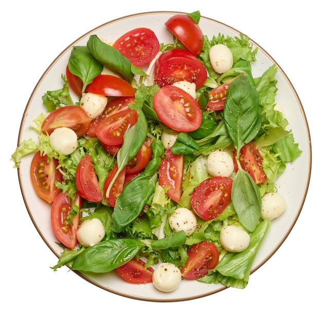 Salade avec mozzarella, tomates cerises et laitue verte dans une assiette ronde blanche