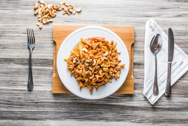 Salade de noix de cajou au poulet servie dans une assiette avec une cuillère et une vue de dessus de tissu sur la table de restauration rapide