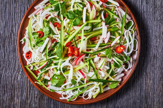 Salade de nouilles de riz et de légumes sur une assiette sur une table en bois, cuisine asiatique, vue horizontale d'en haut, mise à plat