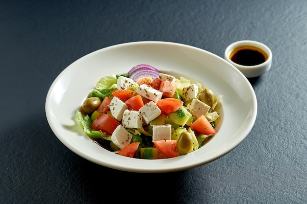 Salade d'olives, tomates et feta dans une assiette blanche. salade grecque