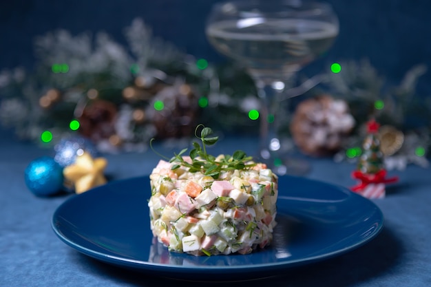 Salade d'Olivier sur assiette bleue, décorée de pousses de pois