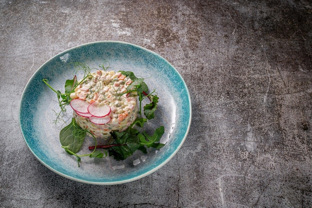 Salade Olivier aux légumes et viande. Apéritif russe traditionnel pour célébrer le nouvel an et noël. Salade d'un plat sur un fond en pierre gris